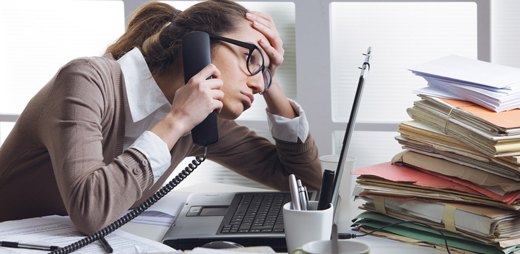 girl hunched over a computer with phone in her hand