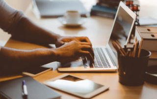 Close up shot of man typing on laptop at his work desk in office